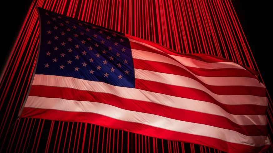 Bandeira dos Estados Unidos tremulando diante de um fundo iluminado por intensas luzes vermelhas verticais, sugerindo um clima de alerta ou crise. A imagem simboliza a crescente preocupação com a dívida pública dos EUA e seu impacto nos juros globais e no mercado financeiro.